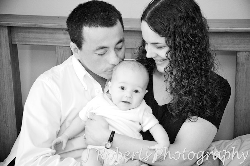 Family of 3 with father kissing baby's head - baby portrait photography sydney